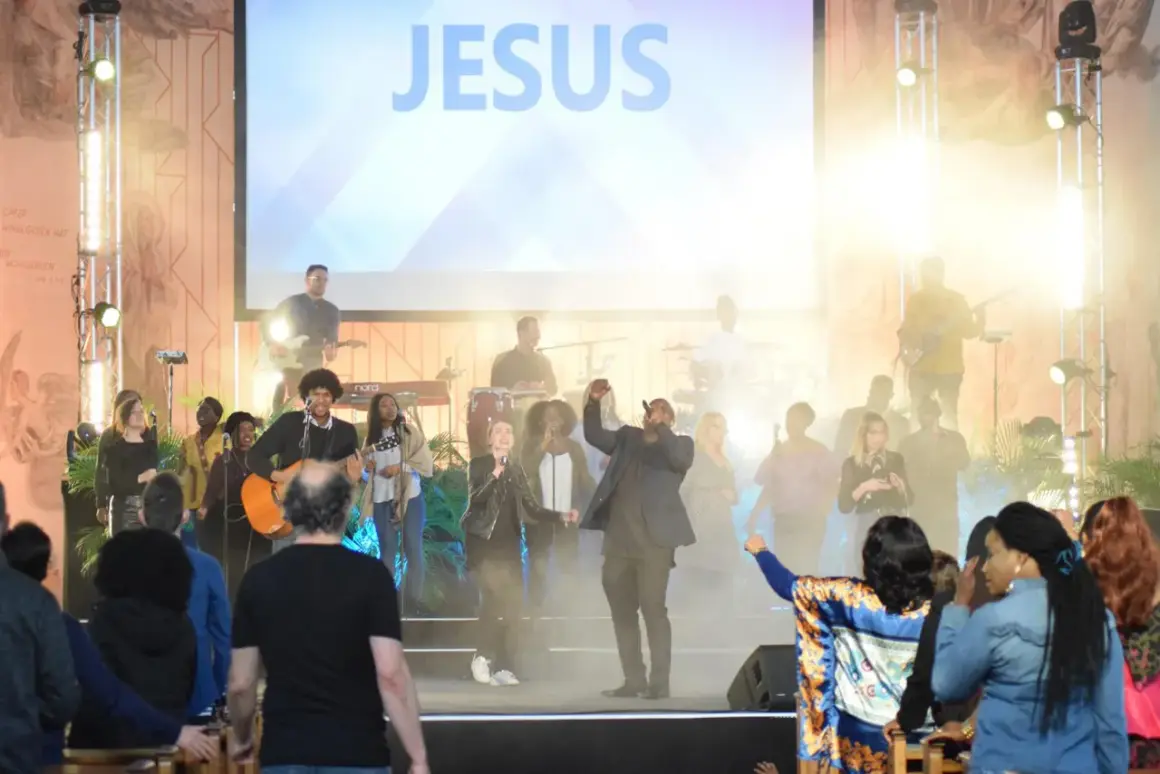 Band spielt bei der New Life Church vor einer Leinwand mit dem Wort "JESUS".
