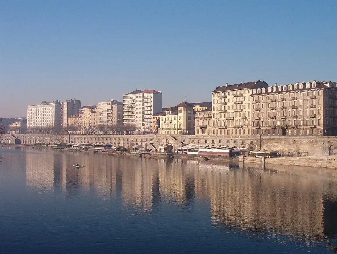 I **murazzi** di Torino si specchiano nel fiume, con palazzi storici e moderni che si affacciano sulla riva.
