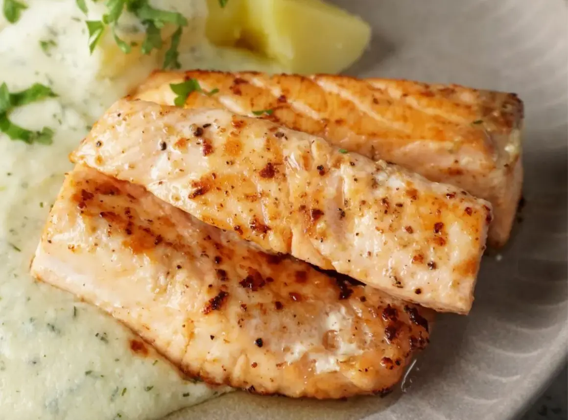 Zwei saftige Lachsfilets, perfekt gebraten, mit cremiger Sauce und Kartoffeln. Ein tolles Gericht für Lachs Rezepte.