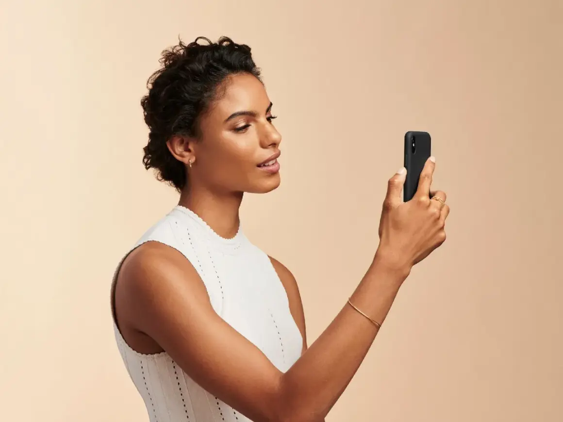 Donna con smartphone, utile per capire come scegliere fondotinta online.
