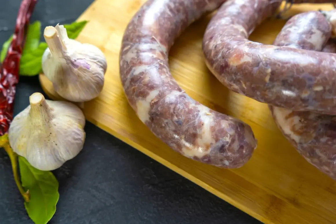 Czosnek i surowa kiełbasa na desce. Ile czosnku na 10 kg mięsa do kiełbasy?