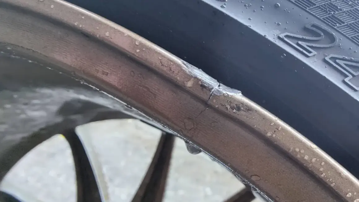 Pęknięta felga aluminiowa z widocznym uszkodzeniem i kroplami wody.
