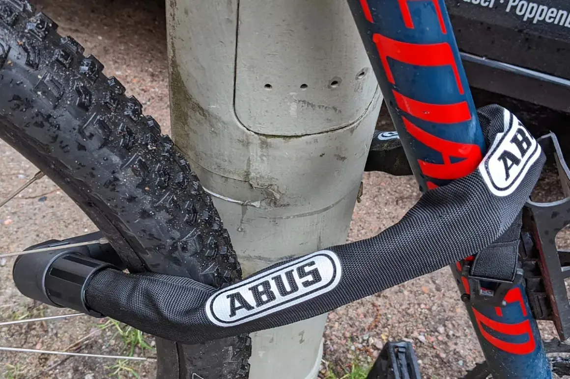 Fahrrad diebstahlschutz: Ein ABUS Kettenschloss sichert das Rad an einem Pfosten.