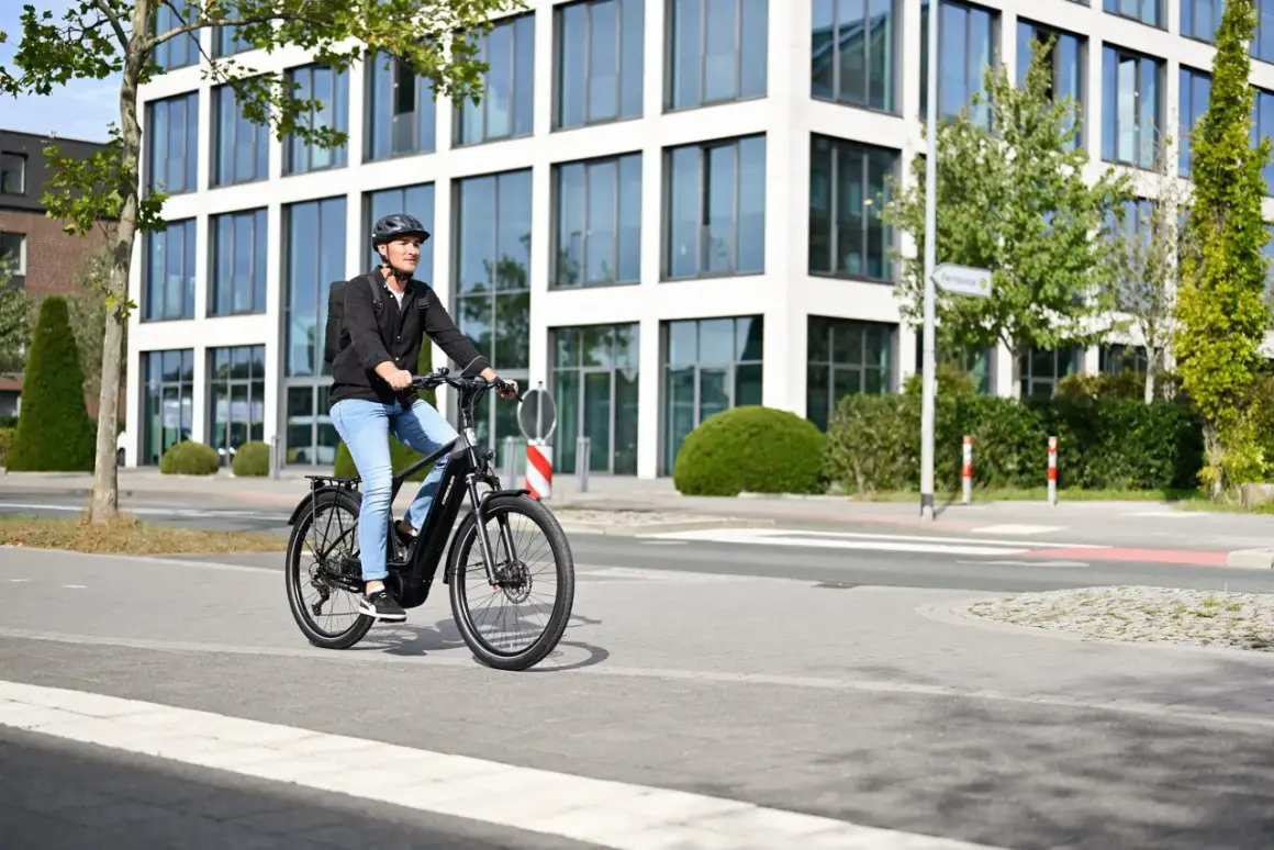 Mann fährt mit E-Bike durch eine moderne Stadt in Deutschland.