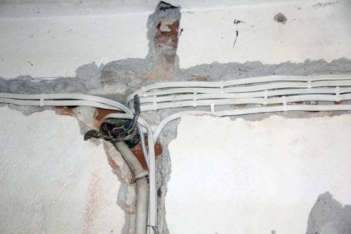 Widoczne przewody elektryczne w peszlach, częściowo ukryte w bruzdach w ścianie. Instalacja aluminiowa w trakcie prac.