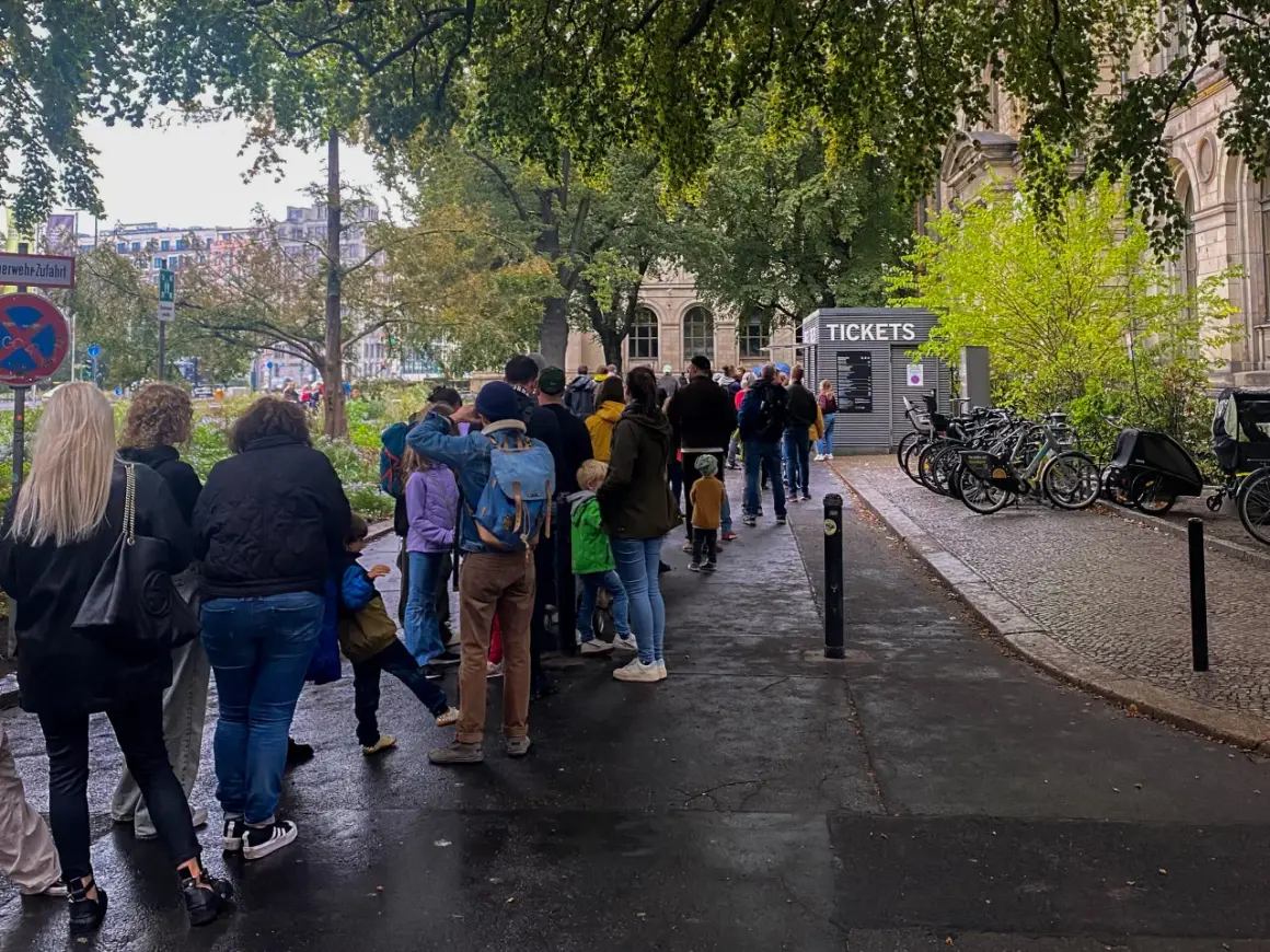 Kolejka do kasy biletowej przy Muzeum Historii Naturalnej w Berlinie. W tle budynek muzeum i drzewa.
