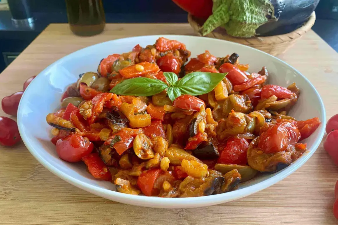 Caponata ricetta semplice: melanzane, peperoni e pomodorini cotti insieme, guarnita con basilico fresco. Un contorno saporito e colorato.