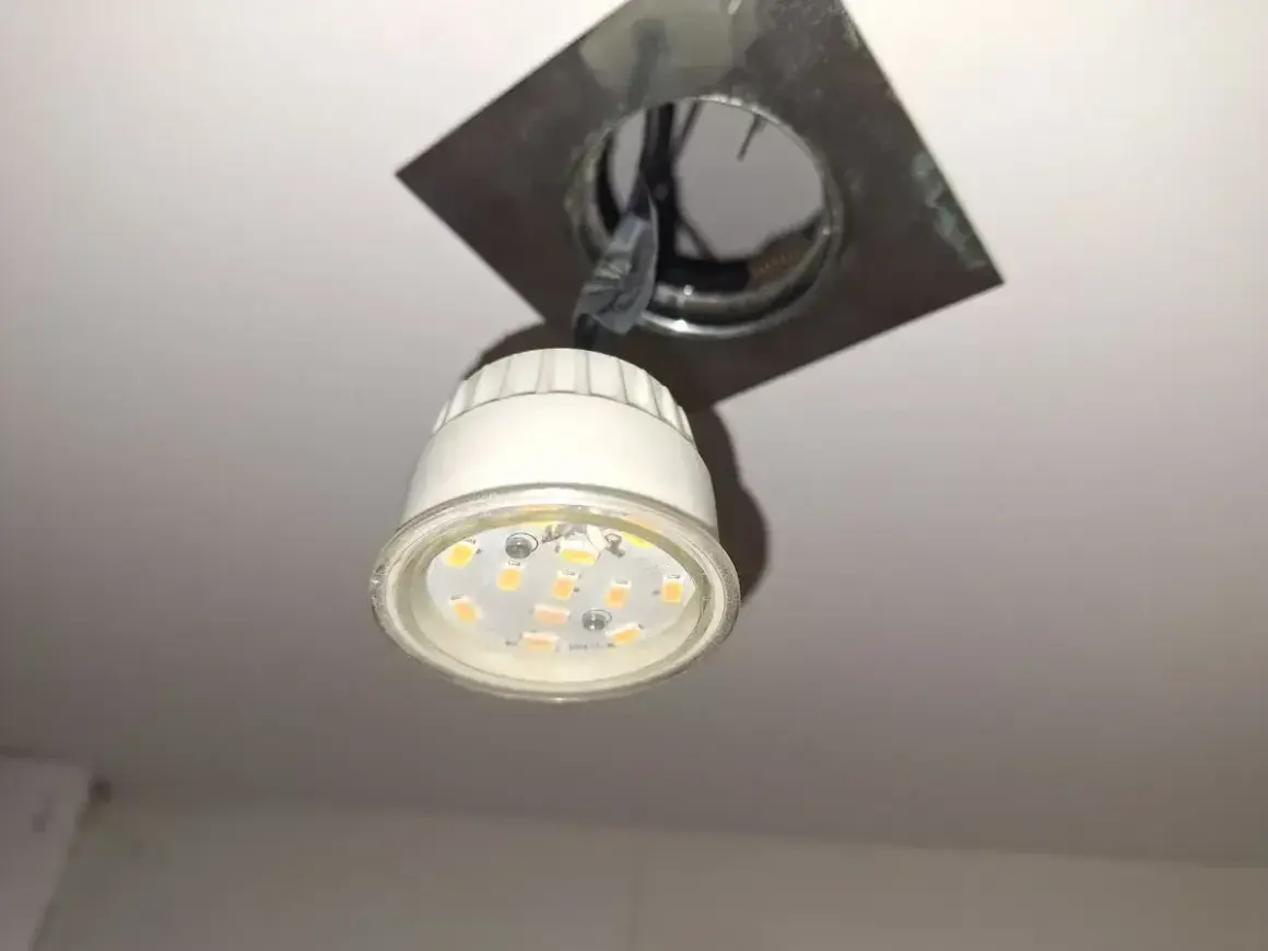 Oprawa natynkowa GU10 z widoczną żarówką LED, zamontowana na suficie.