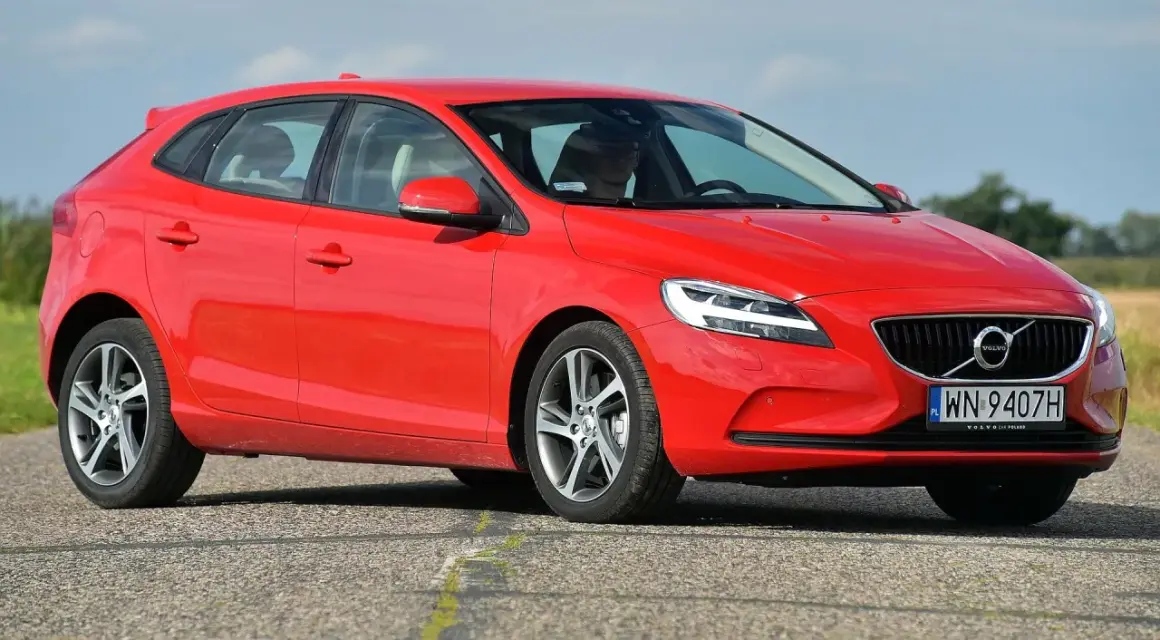 Czerwone Volvo V40 D2 z polskimi tablicami rejestracyjnymi jedzie po asfaltowej drodze.