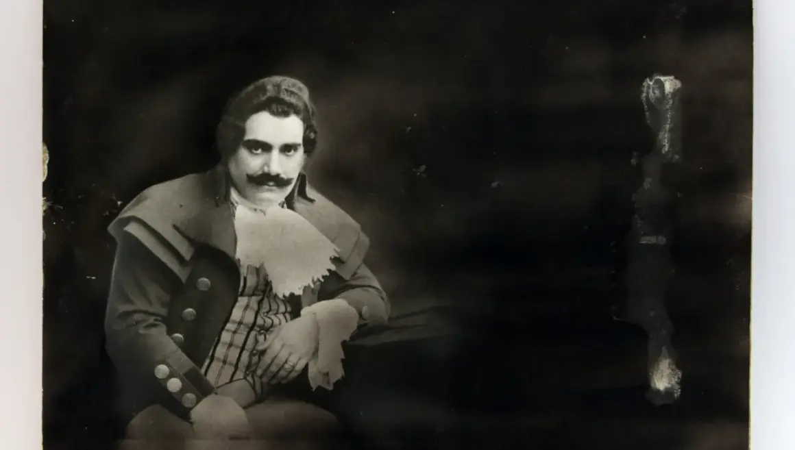 Ritratto di Enrico Caruso, la cui causa morte è ancora oggetto di dibattito. Indossa un costume d'epoca con baffi imponenti.