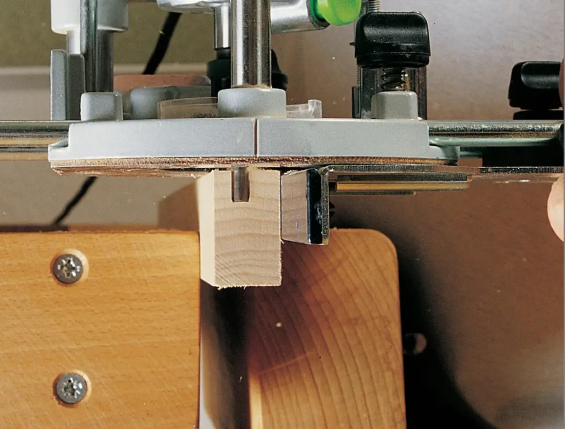 Utilisation d'un gabarit rainure défonceuse pour créer une entaille précise dans une pièce de bois.