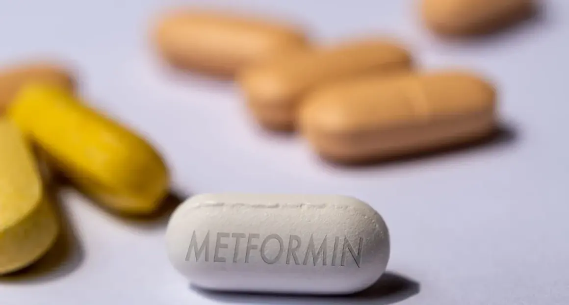 Eine weiße Tablette mit der Aufschrift "Metformin" liegt im Vordergrund. Im Hintergrund sind unscharfe gelbe und orangefarbene Pillen zu sehen. Forschung untersucht, ob Metformin bei Demenz helfen kann.