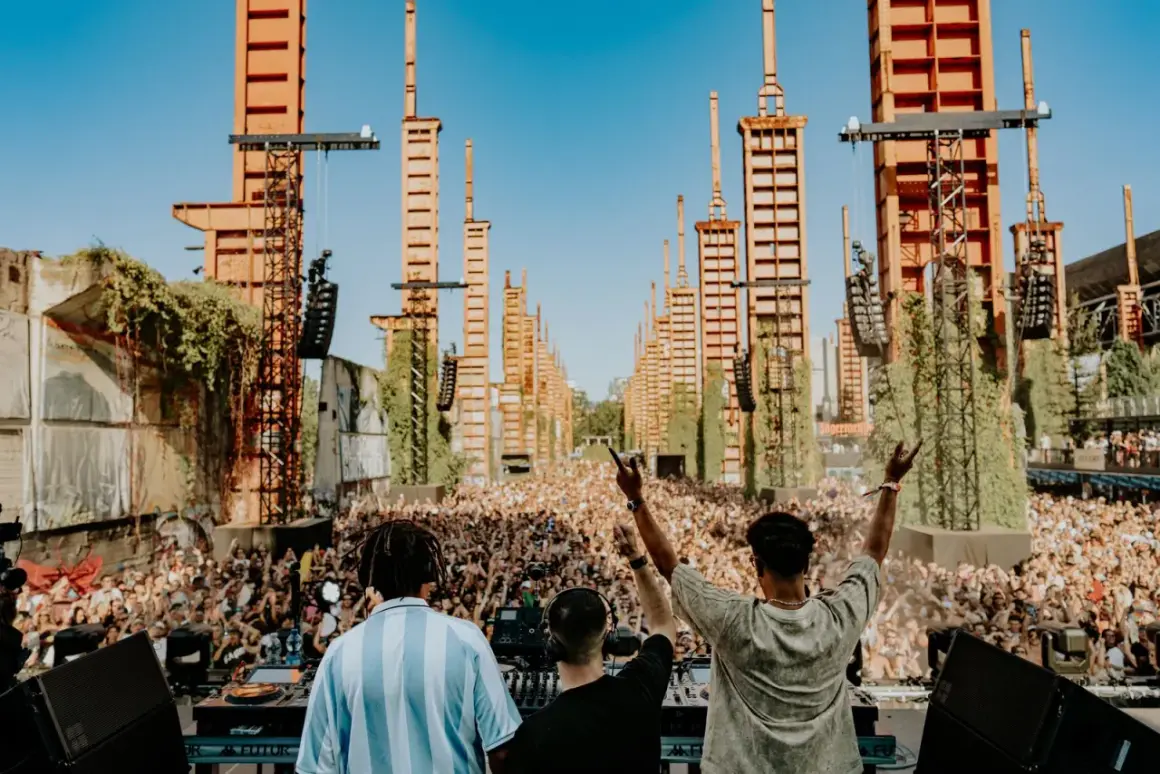 DJ set al futur festival torino, con una folla immensa e torri arancioni che si ergono verso il cielo.