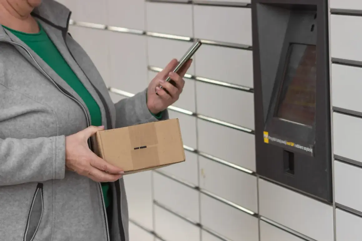 Kobieta z paczką w ręku korzysta z telefonu przy automacie InPost. Szybkie przekierowanie paczki jest teraz łatwiejsze.
