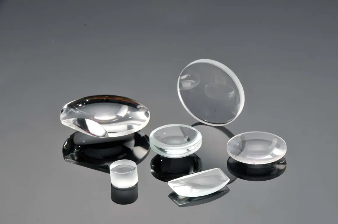 Collezione di lenti ottiche di varie forme, realizzate in vetro minerale o zaffiro, su superficie riflettente.