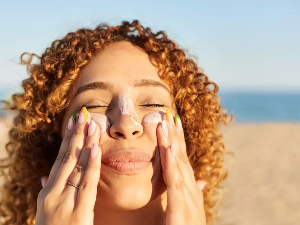 Frauenhände verteilen Sonnencreme mit Methylene bis-benzotriazolyl tetramethylbutylphenol auf der Nase.