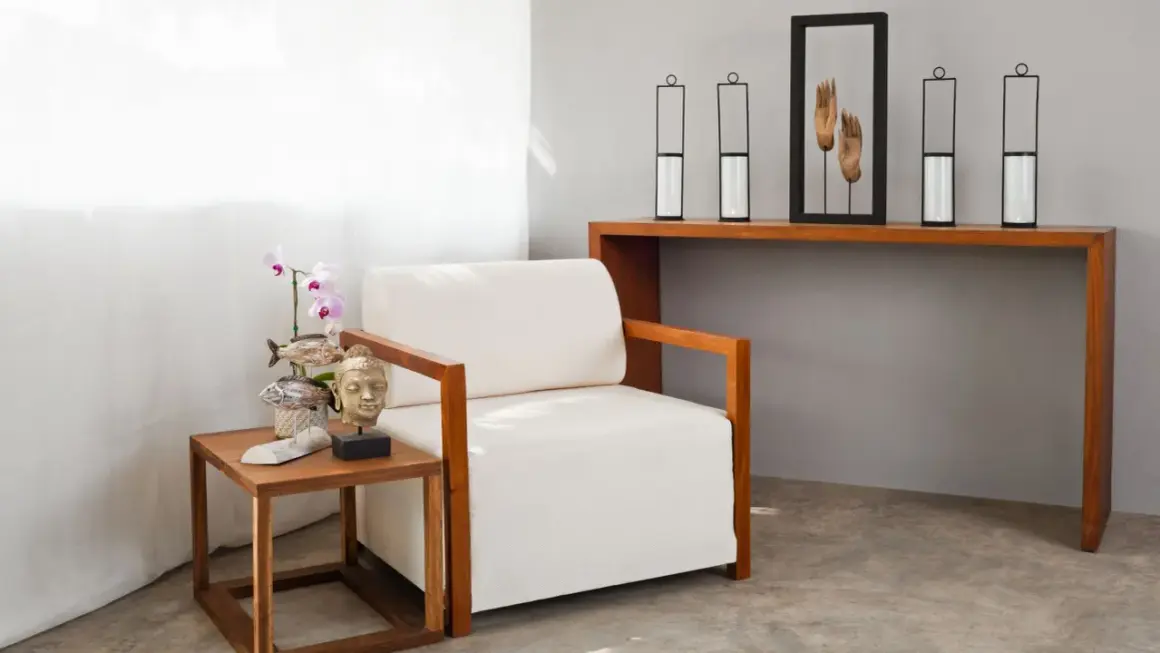 Kreative Ideen für eine tote Ecke im Wohnzimmer: Sessel, Beistelltisch mit Buddha-Kopf und Orchidee, Konsolentisch mit Kerzenhaltern und Händen-Deko.