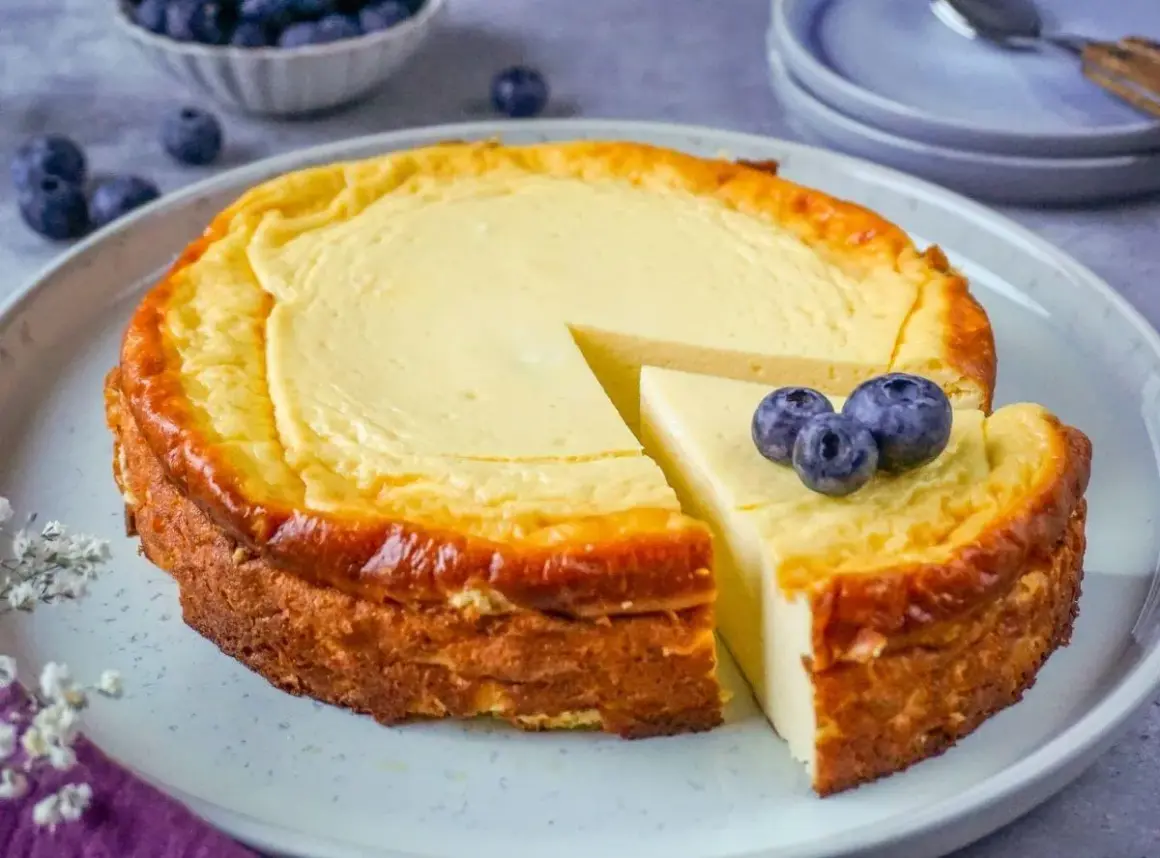 Ein saftiger Quarkkuchen ohne Boden, goldbraun gebacken und mit frischen Blaubeeren garniert. Ein Genuss für jeden Kaffeetisch!