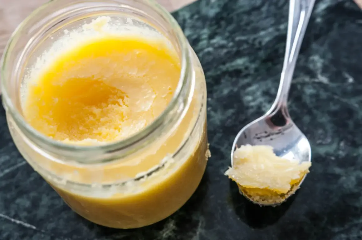 En burk med gyllene ghee och en sked med lite av det. Perfekt för ditt ghee recept!