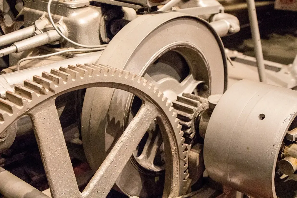Metalowe koła zębate, w tym duża zwolnica, tworzą skomplikowany mechanizm napędowy.