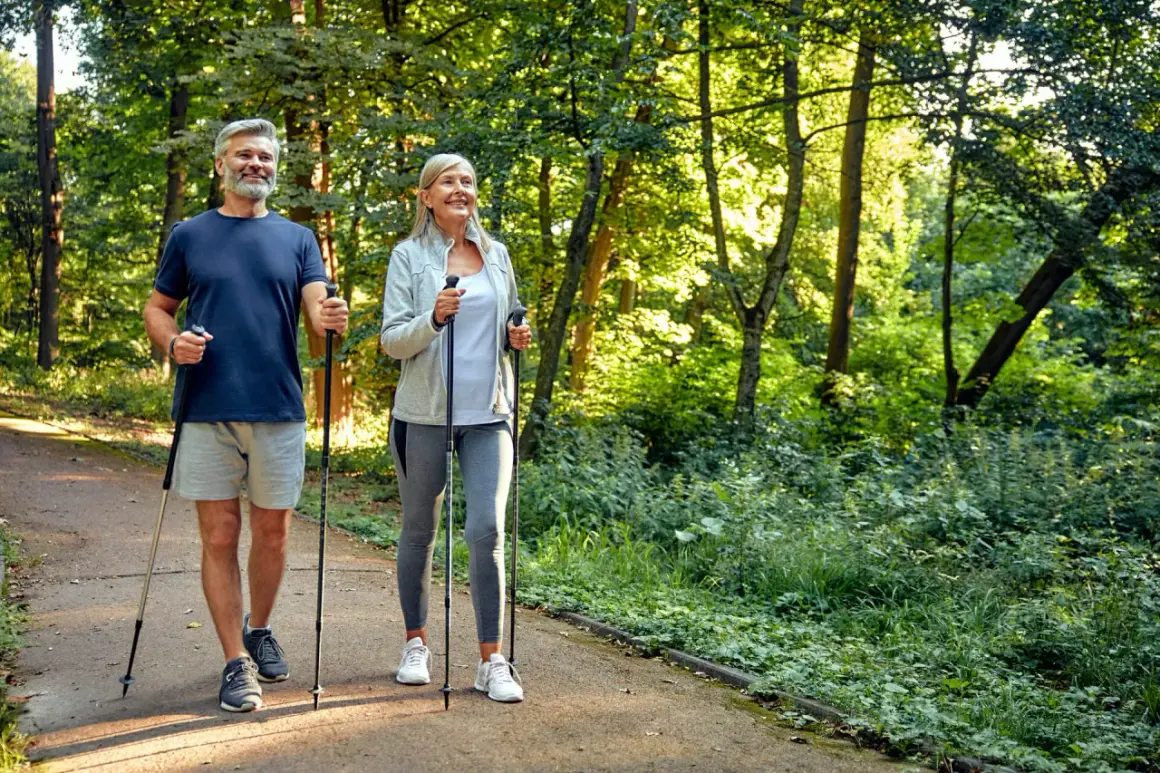 Älteres Paar genießt Nordic Walking im Wald. Eine gute Aktivität bei Bandscheibenvorfall zur Stärkung der Rückenmuskulatur.