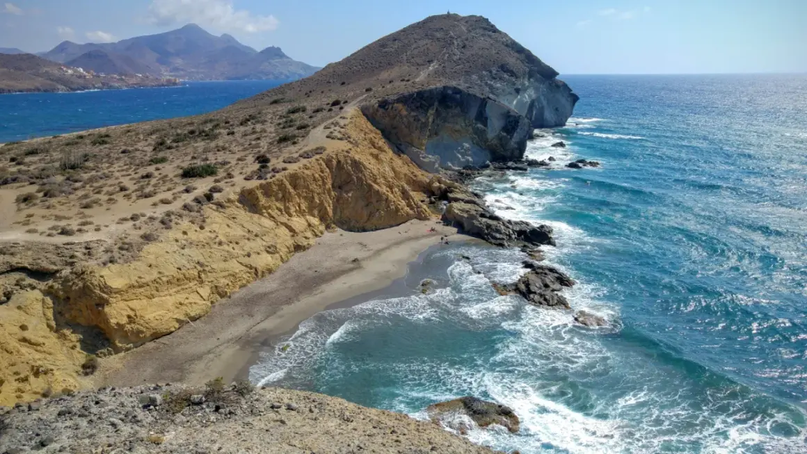 Paisaje de la cala amarilla en Almería, con acantilados dorados, arena y mar azul turquesa.