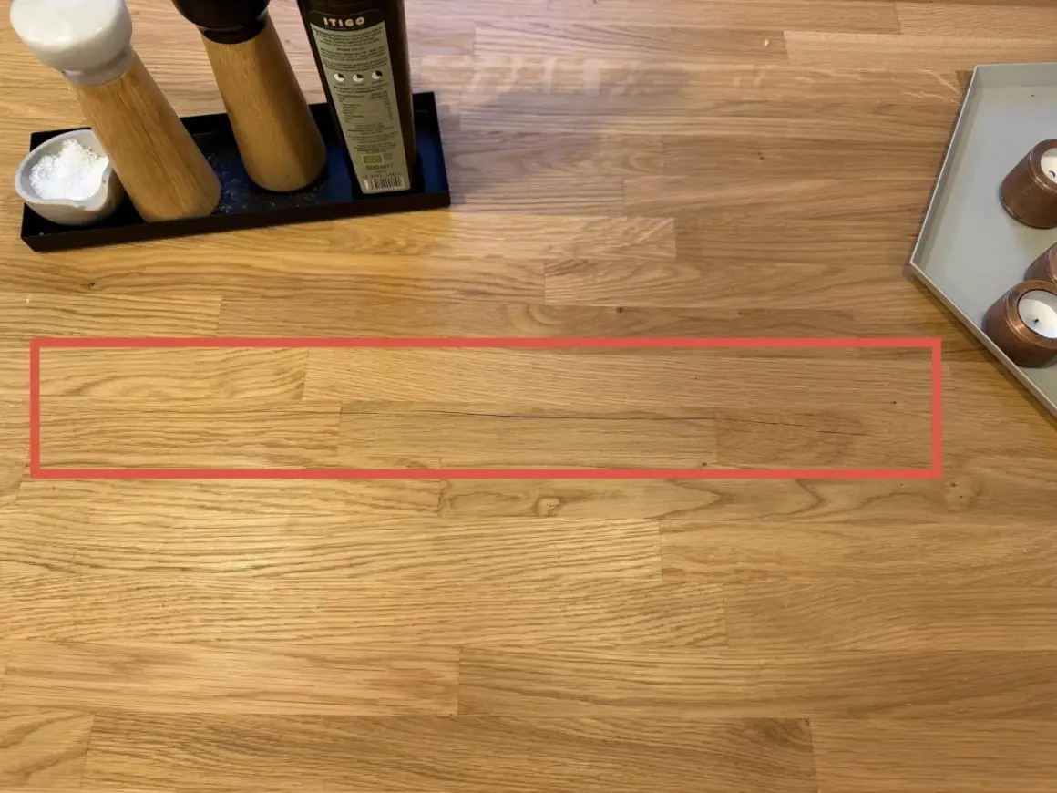 Une fissure visible sur une table en bois, nécessitant une réparation.