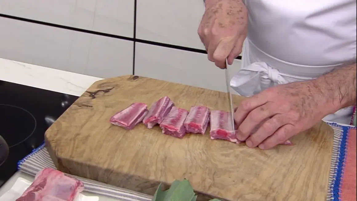 Chef corta costillas de cerdo en trozos para una deliciosa terrina de costilla.
