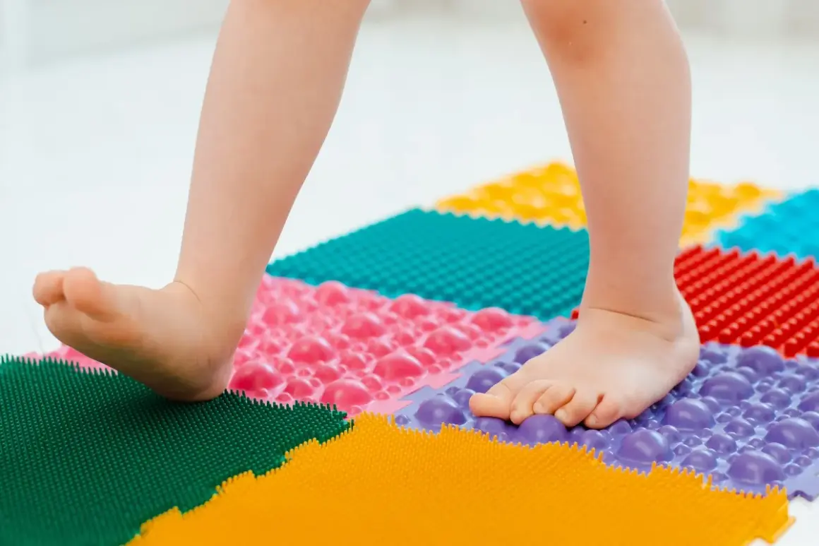 Niño camina sobre un tapete terapéutico de colores para fortalecer sus pies planos.