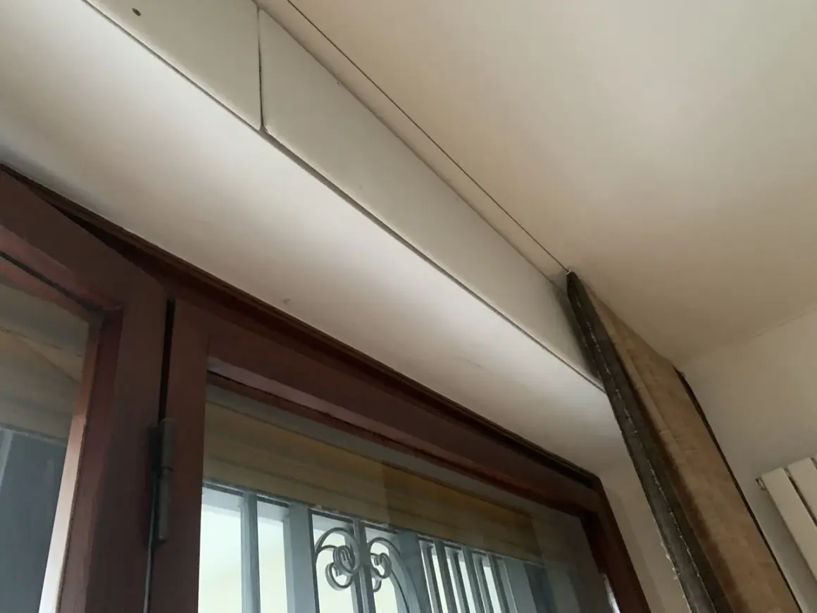 Dettaglio di un cassonetto tapparelle in fase di rimozione, con pannello in legno appoggiato.