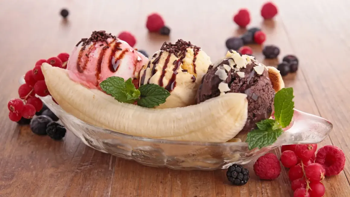 Ein klassisches Banana Split Eis mit drei Kugeln Eis, Banane, Beeren und Schokoladensauce.