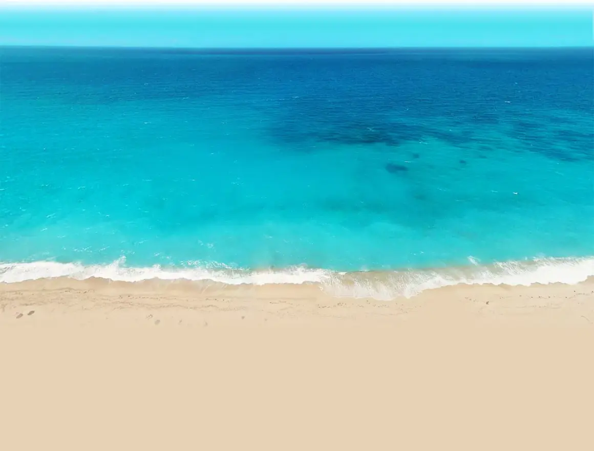 Vista aérea de una playa de arena dorada y aguas turquesas, como las de el palmer almeria, con olas rompiendo suavemente.