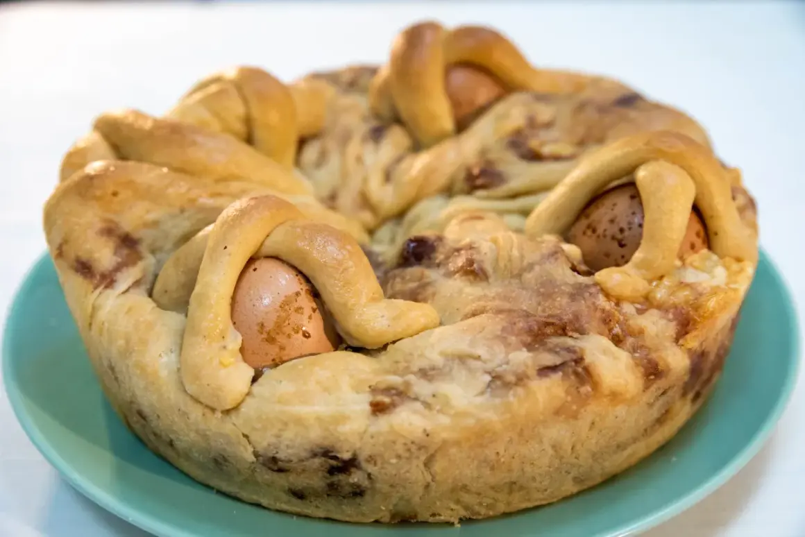 Casatiello napoletano ricetta della nonna: un rustico profumato con uova intere incastonate nell'impasto intrecciato, pronto per essere gustato.