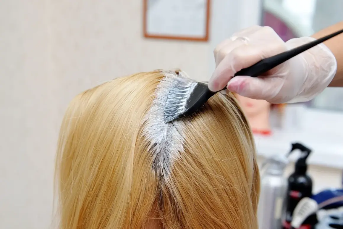 Fryzjerka nakłada farbę na włosy klientki o odcieniu strawberry blonde.
