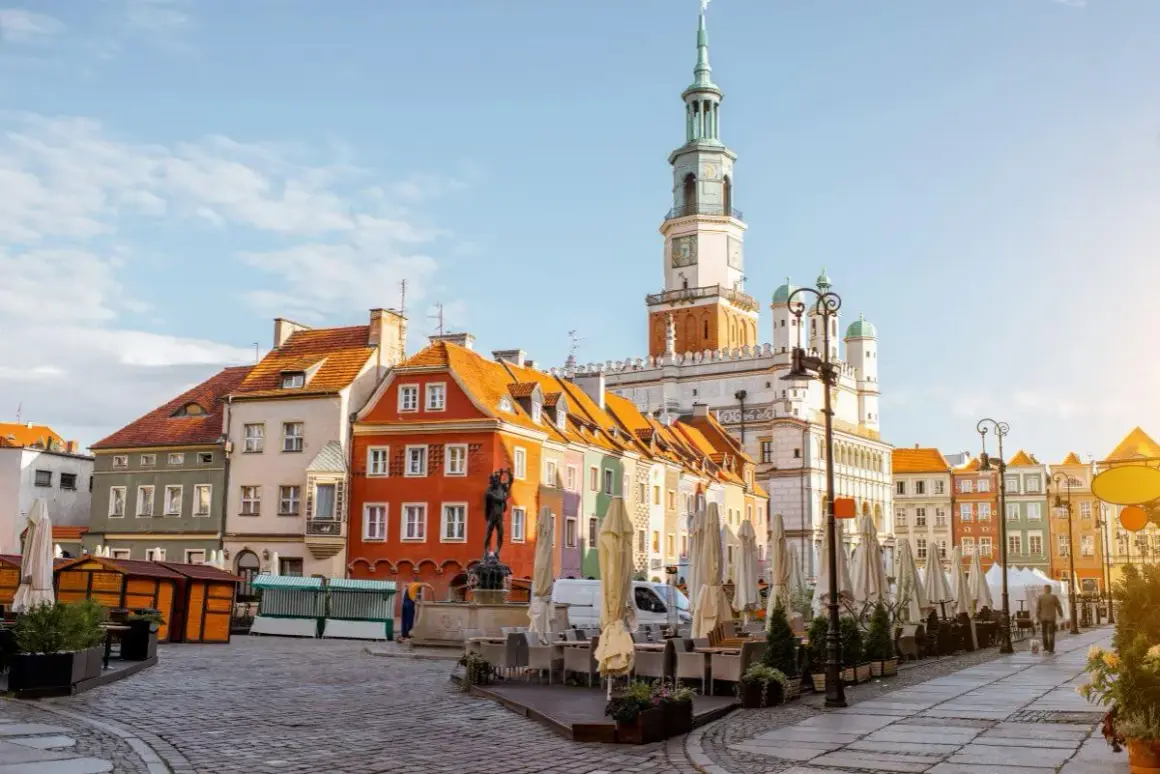 Kolorowe kamienice na Starym Rynku w Poznaniu, gdzie czeka na Ciebie poznań miasto doznań. Ratusz góruje nad placem pełnym ogródków kawiarnianych.