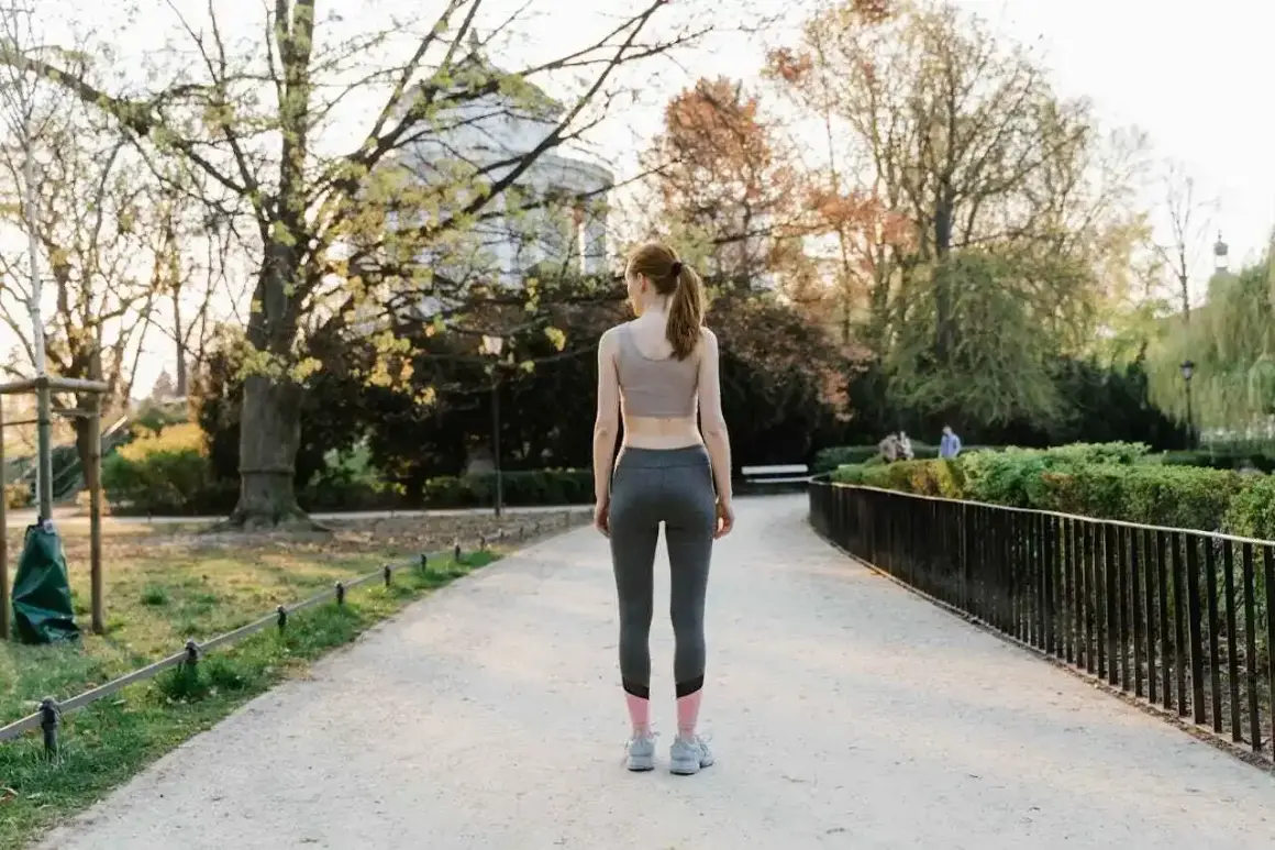 Femme en tenue de sport marchant dans un parc, une façon naturelle de muscler son périnée en profitant du grand air.