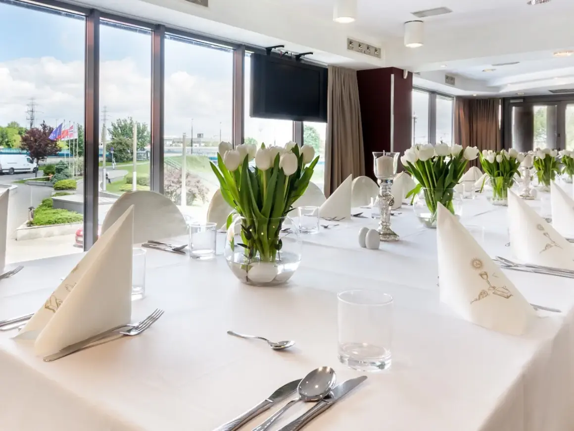 Elegancko nakryty stół z białymi tulipanami, idealny na uroczystość. Zastanawiasz się, ile trwa komunia w restauracji? To zależy od wielu czynników, ale zazwyczaj trwa kilka godzin.