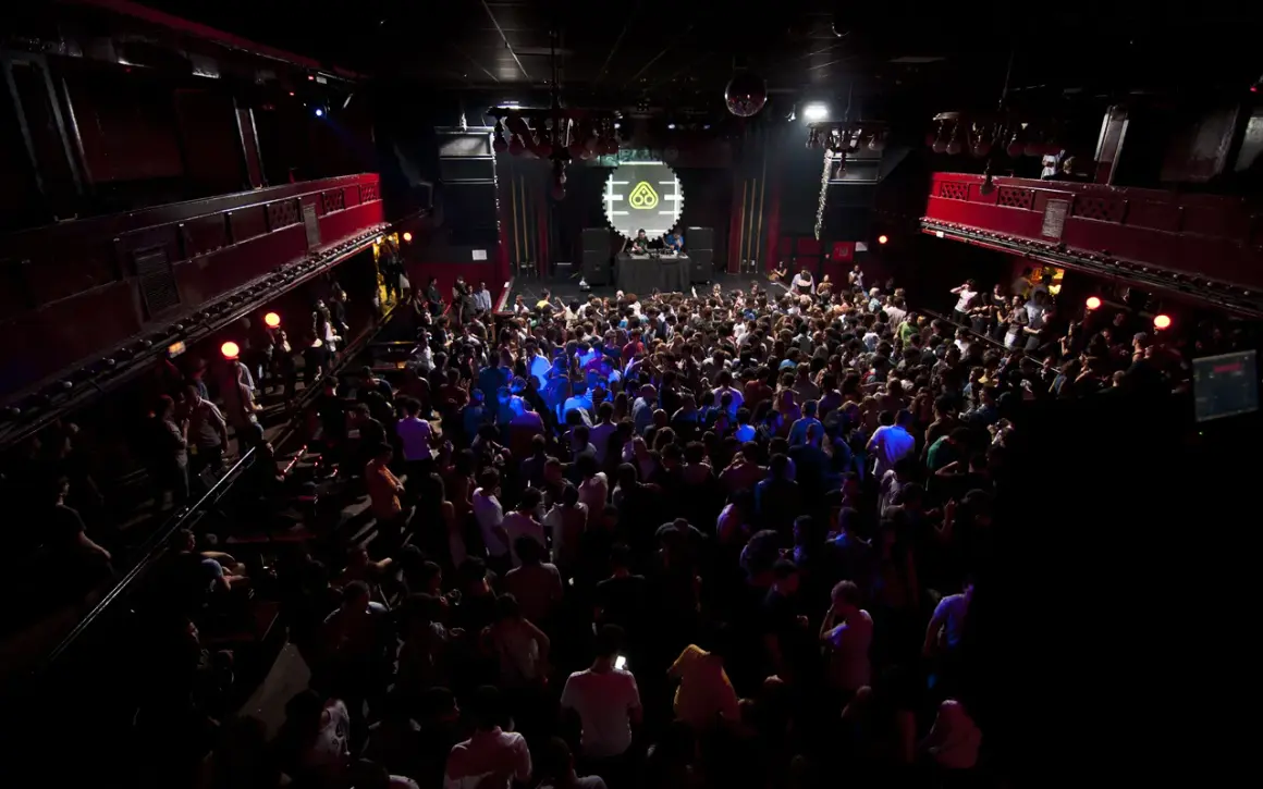 Folla in delirio al Nitsa Club, luci soffuse e musica pulsante.
