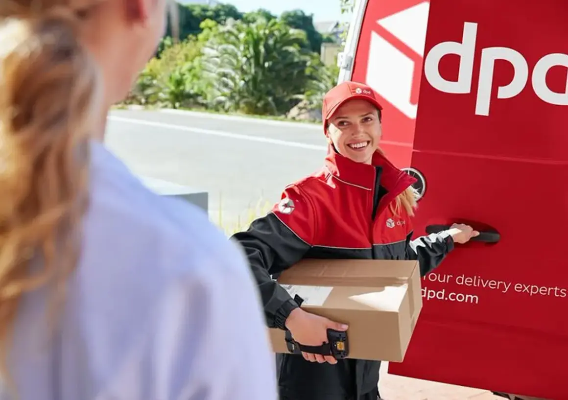 Kurierka DPD z uśmiechem przekazuje przesyłkę do doręczenia w punkcie pickup.