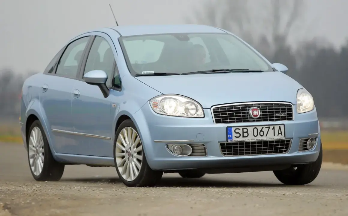Jasnoniebieski Fiat Linea z polskimi tablicami SB 0671A jedzie po drodze.