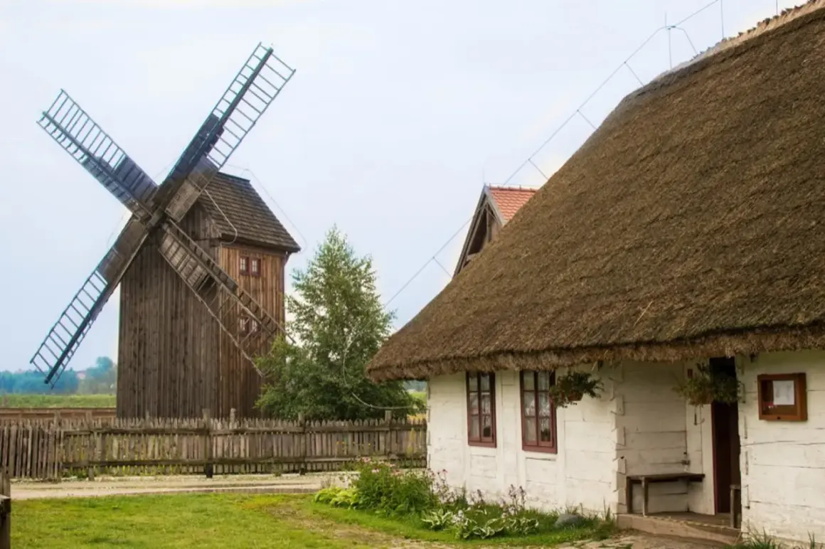 Drewniany wiatrak i biały domek z krytym strzechą dachem tworzą malowniczą zagrodę młynarską w Uniejowie.