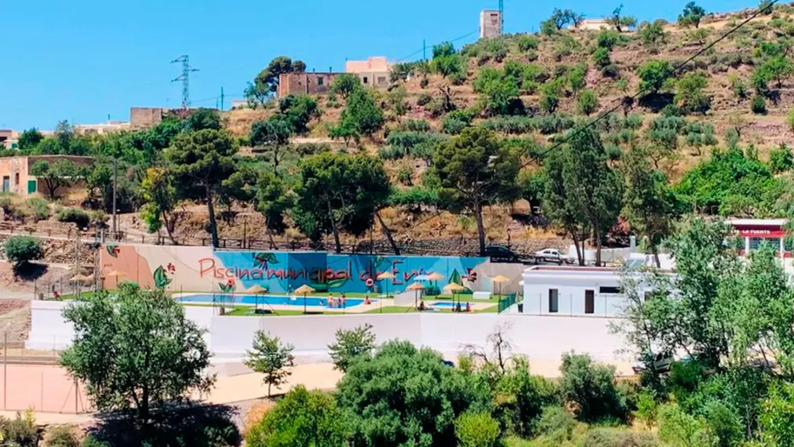 Piscina municipal en el oeste de Almería, rodeada de vegetación y colinas. Un oasis refrescante bajo el sol andaluz.