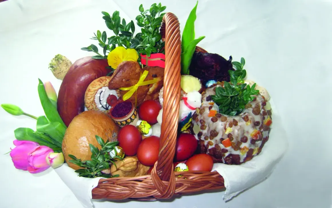 Koszyk wielkanocny z tradycyjnym święceniem pokarmów: chleb, kiełbasa, jajka, babka, zieleń i ozdoby.
