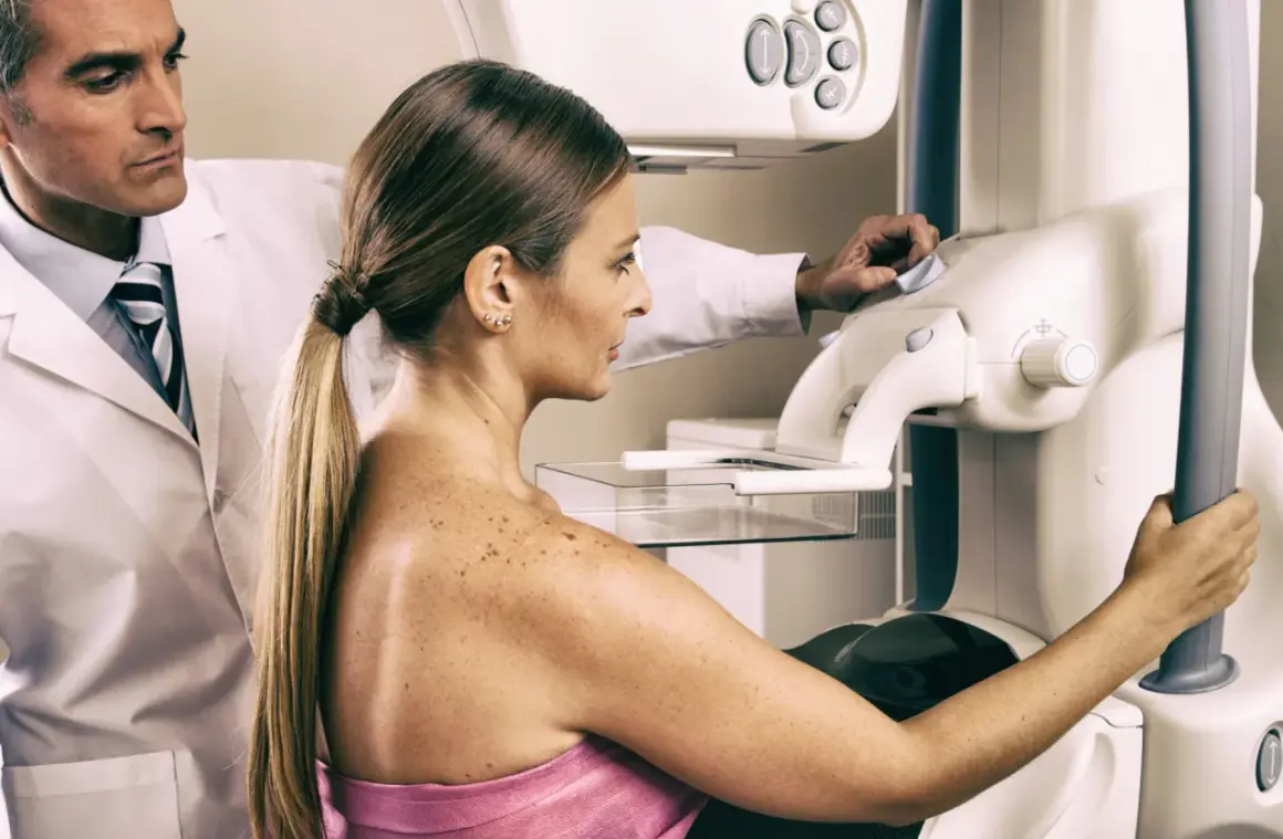 Lekarz nadzoruje badanie mammograficzne, które może być wstępem do biopsji gruboigłowej. Kobieta przygotowuje się do procedury.