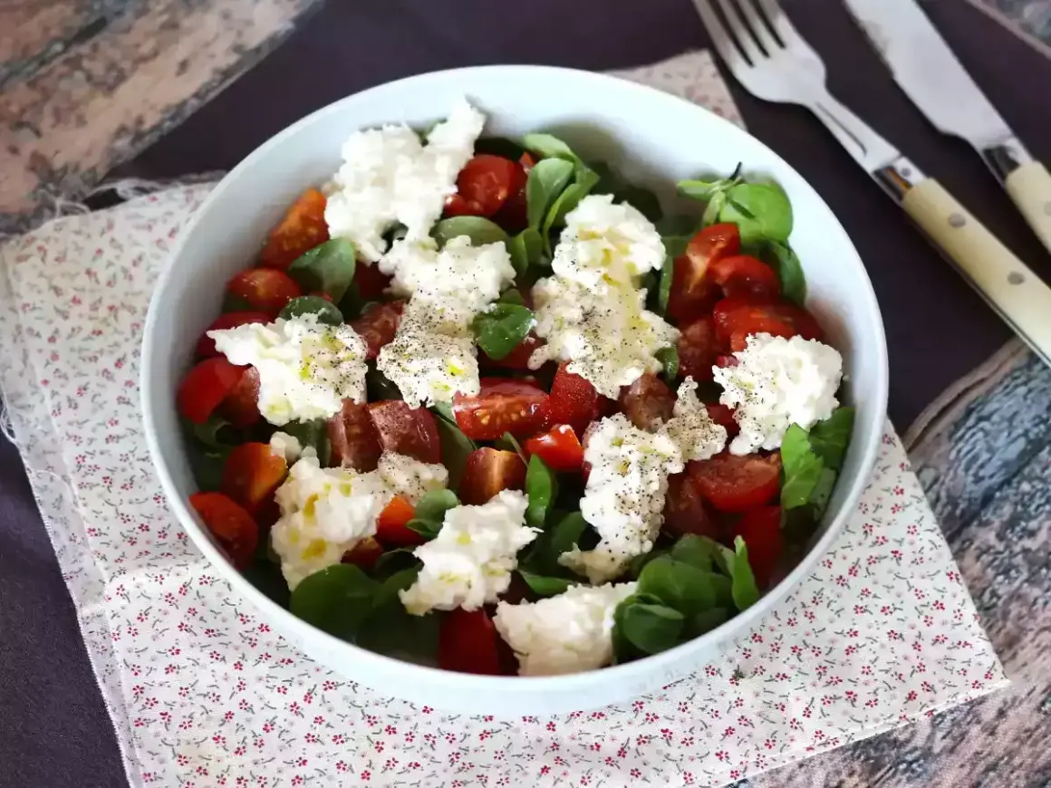 En härlig sallad med tomater, gröna blad och krämig burrata. Perfekt för ett enkelt burrata recept.