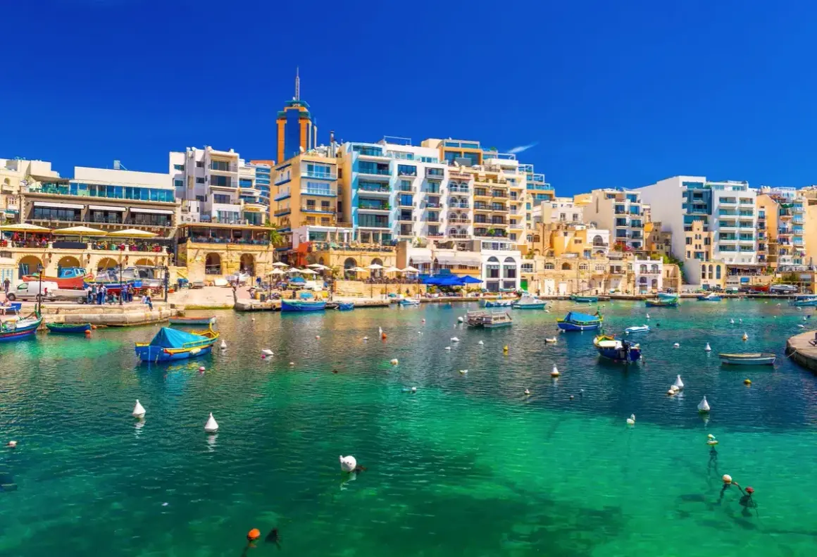 Malta, St Julian's: malowniczy port z turkusową wodą, łodziami i nowoczesnymi budynkami.
