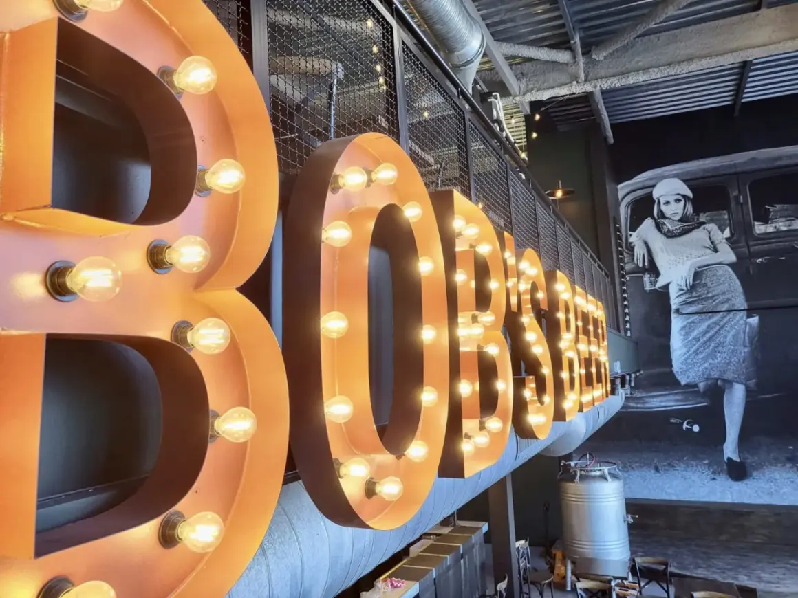 Lettre enseigne lumineuse "BOBSTER" sur fond d'une fresque vintage.