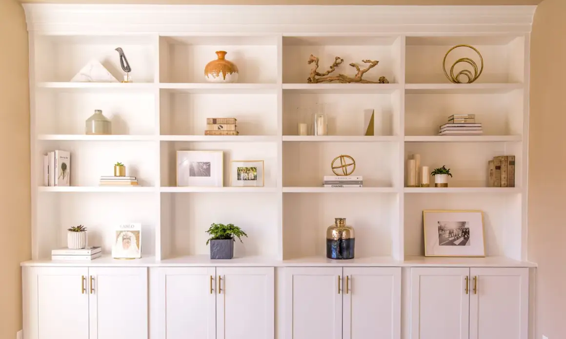 A beautifully styled built-in shelving unit showcases decorative objects, books, and framed photos.