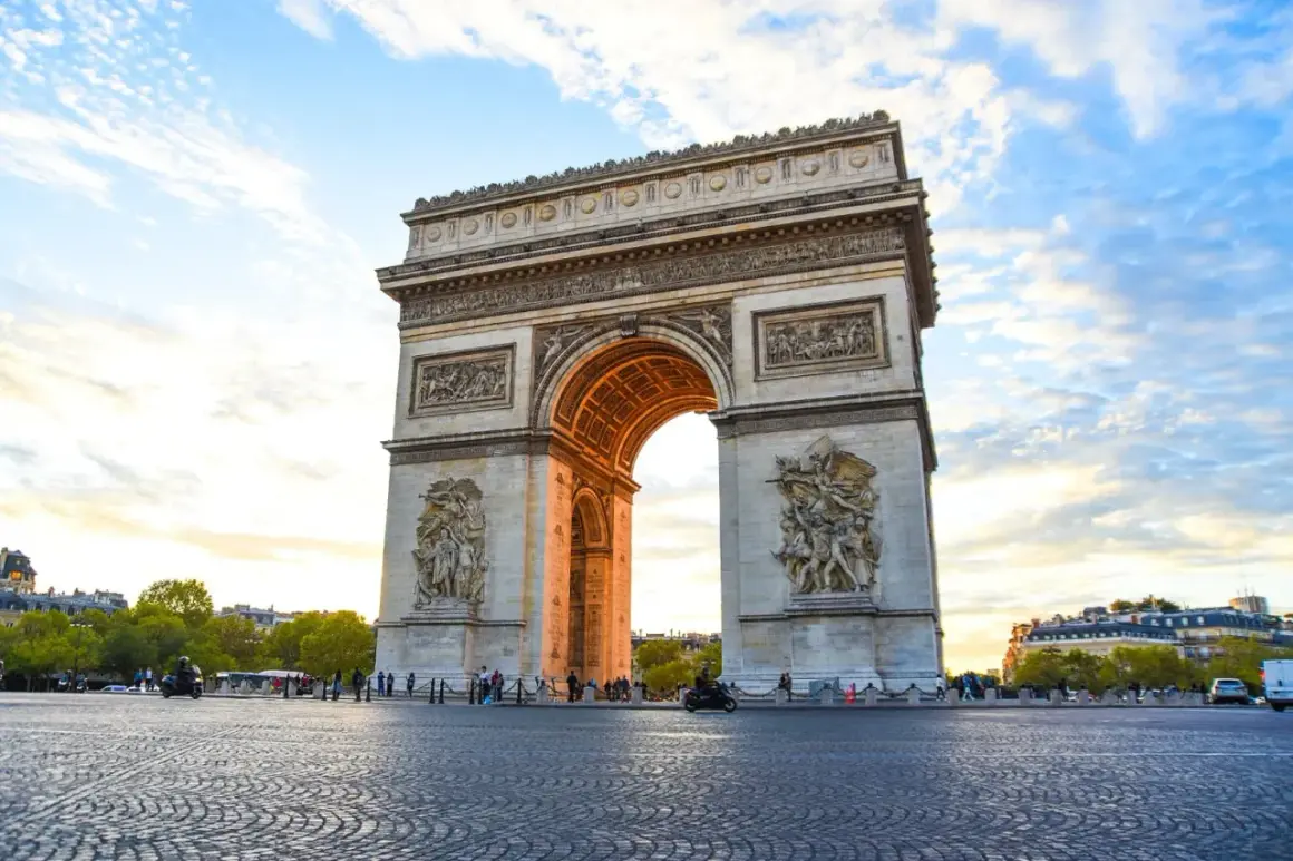 Triumfbågen, en av de mest kända byggnaderna i Paris, reser sig majestätiskt mot en molnig himmel.