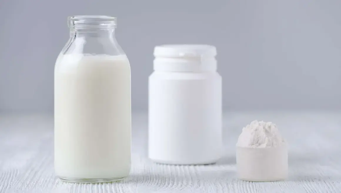 Bottiglia di latte, contenitore bianco e misurino con polvere. Le proteine del latte si trovano in questi prodotti.